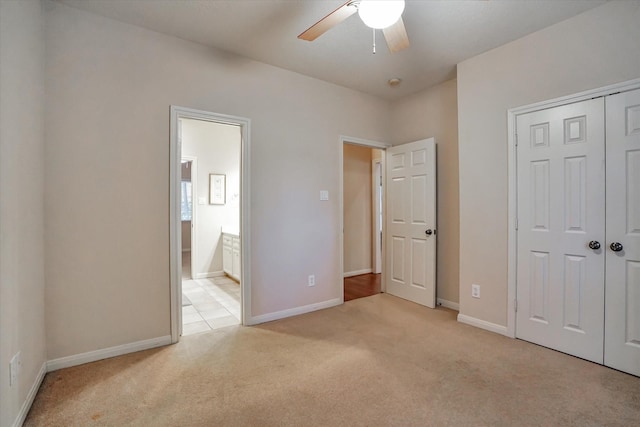 unfurnished bedroom with a closet, ceiling fan, ensuite bathroom, and light colored carpet