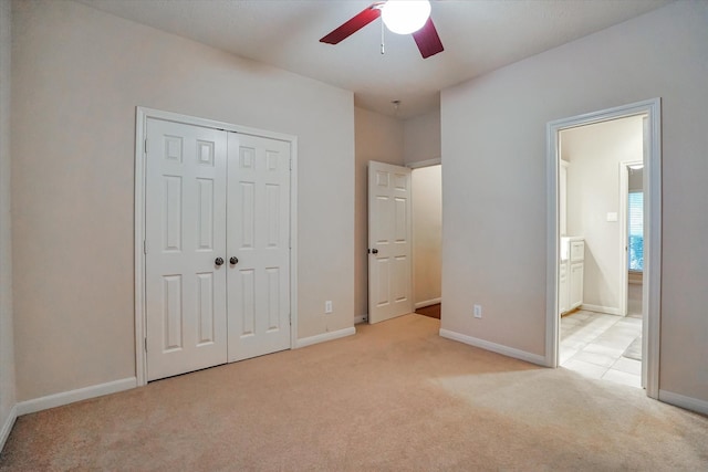 unfurnished bedroom with connected bathroom, light colored carpet, a closet, and ceiling fan