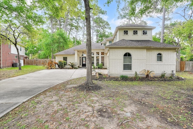 15420 Winterhaven Dr, Tomball, TX 77377 - view of front facade featuring fence, brick siding, a shingled roof, concrete driveway, and cooling unit