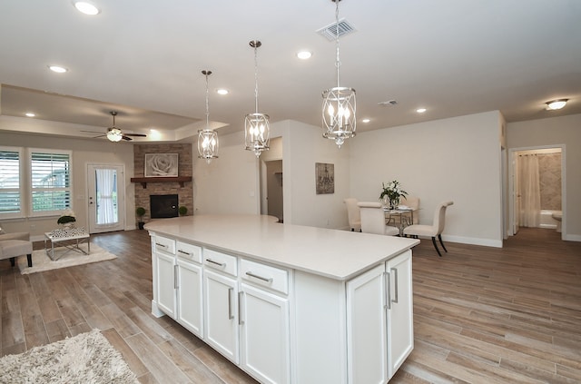 kitchen featuring pendant lighting, white cabinets, light wood-type flooring, and a kitchen island