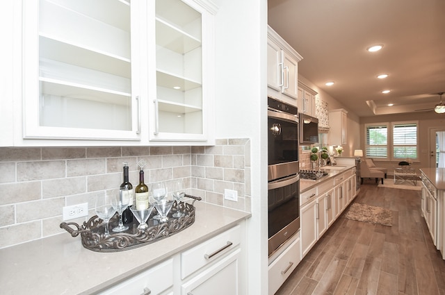 kitchen with backsplash, appliances with stainless steel finishes, ceiling fan, white cabinetry, and dark hardwood / wood-style floors