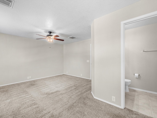 unfurnished room with ceiling fan, light carpet, and a textured ceiling