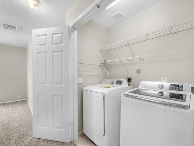 washroom with light carpet, washer and dryer, and a textured ceiling