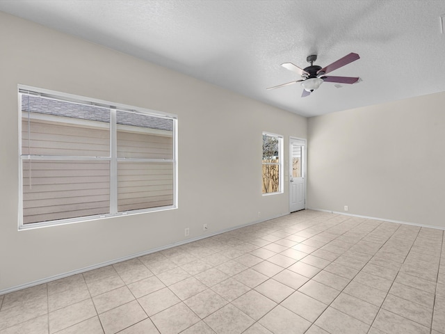 tiled empty room with ceiling fan and a textured ceiling