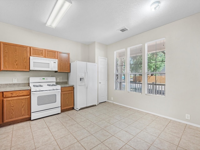 kitchen featuring white appliances, a textured ceiling, and light tile patterned floors