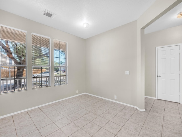 spare room featuring a healthy amount of sunlight, a textured ceiling, and light tile patterned floors