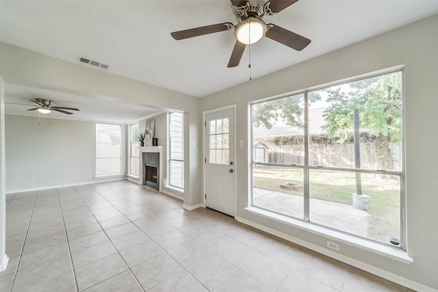 unfurnished living room with ceiling fan, light tile patterned floors, and plenty of natural light