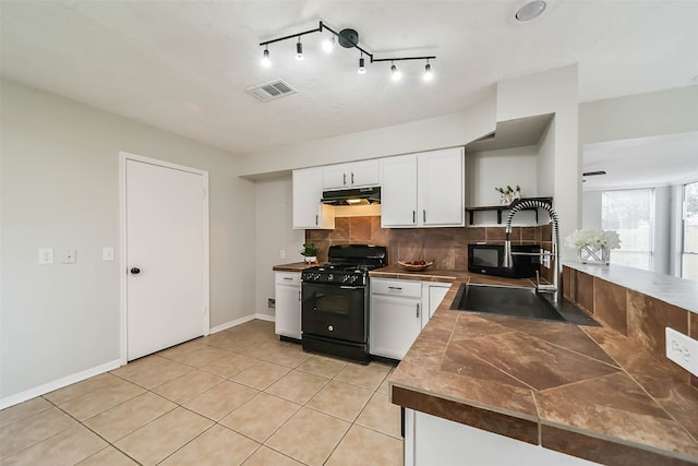 kitchen featuring white cabinets, backsplash, light tile patterned flooring, black range with gas cooktop, and sink