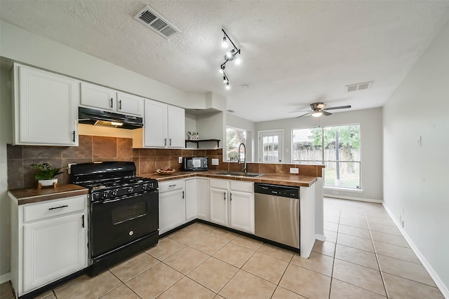 kitchen featuring backsplash, white cabinetry, light tile patterned flooring, black appliances, and sink