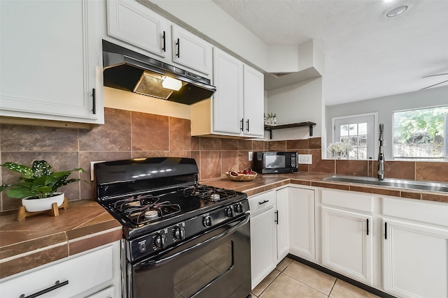 kitchen with black appliances, light tile patterned flooring, sink, tile countertops, and white cabinets