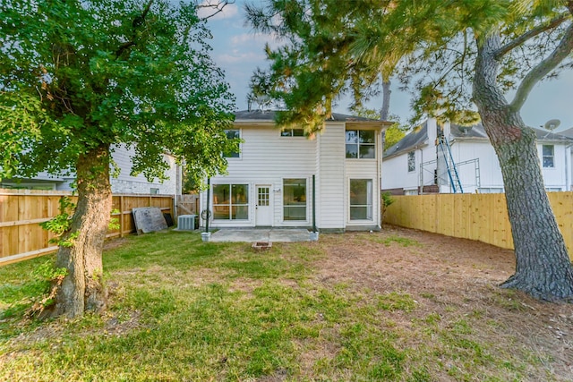 rear view of house featuring a patio, central AC, and a lawn