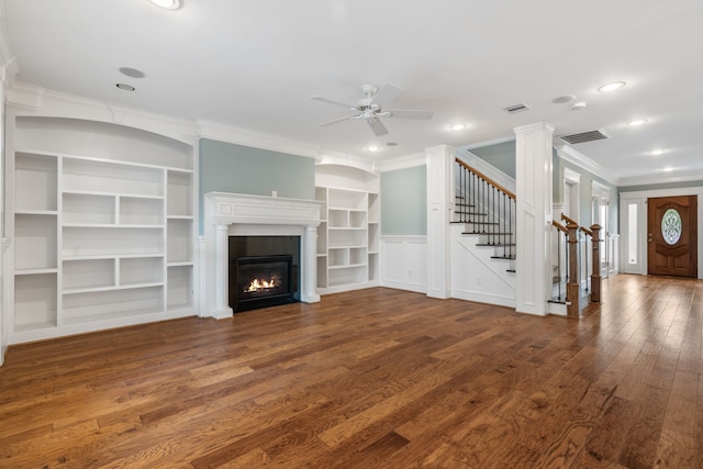 unfurnished living room featuring built in features, ornate columns, ceiling fan, ornamental molding, and dark hardwood / wood-style floors