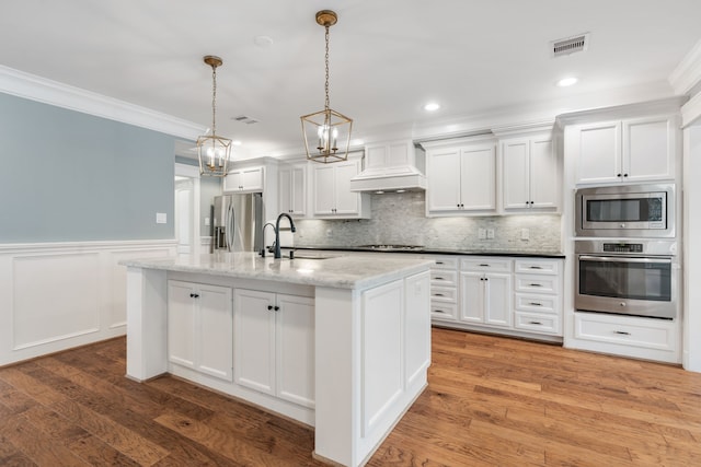 kitchen with wood-type flooring, white cabinetry, stainless steel appliances, pendant lighting, and a center island with sink