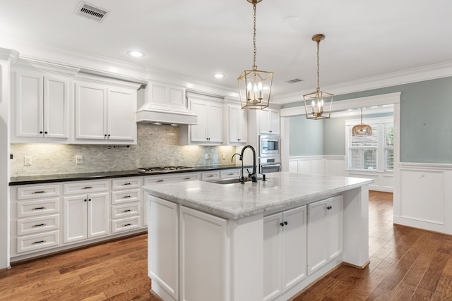 kitchen with hardwood / wood-style floors, appliances with stainless steel finishes, decorative light fixtures, and white cabinetry