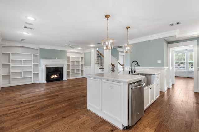 kitchen featuring a kitchen island with sink, sink, decorative light fixtures, stainless steel dishwasher, and white cabinetry