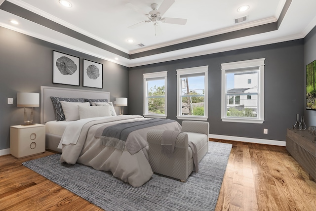 bedroom featuring crown molding, hardwood / wood-style flooring, a tray ceiling, and ceiling fan