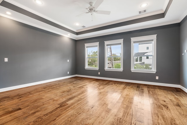 unfurnished room with light hardwood / wood-style floors, ornamental molding, a raised ceiling, and ceiling fan