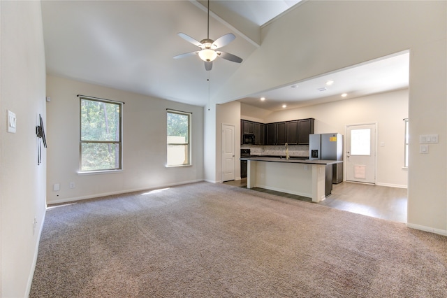 kitchen featuring sink, a kitchen bar, ceiling fan, a center island with sink, and stainless steel refrigerator with ice dispenser