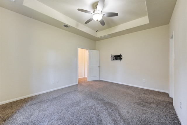 unfurnished room featuring carpet floors, a tray ceiling, and ceiling fan