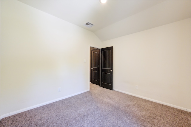 carpeted empty room featuring vaulted ceiling