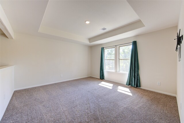 carpeted empty room featuring a tray ceiling