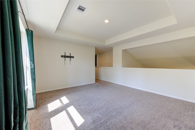 empty room with light colored carpet and a raised ceiling