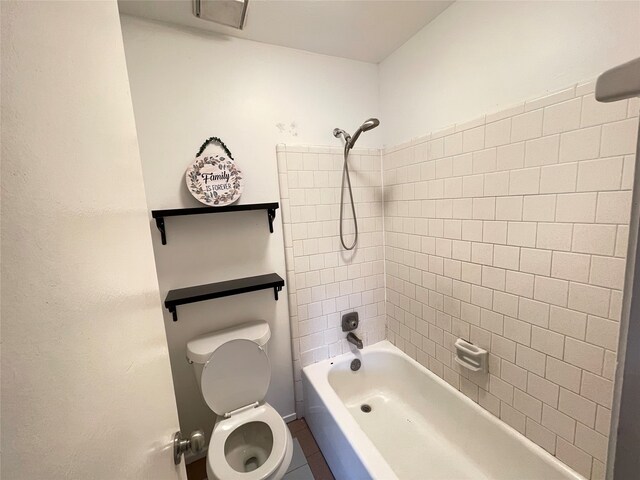 bathroom with toilet, tiled shower / bath combo, and tile patterned floors