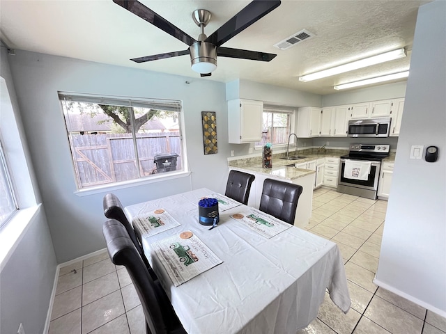 dining area with sink, ceiling fan, and light tile patterned floors