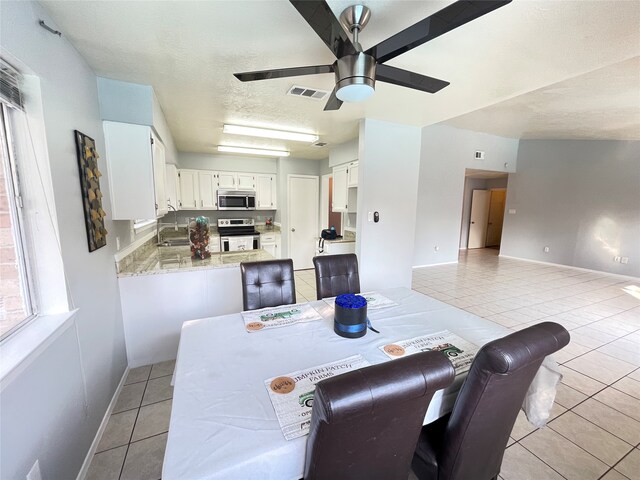 tiled dining space featuring sink, a textured ceiling, and ceiling fan