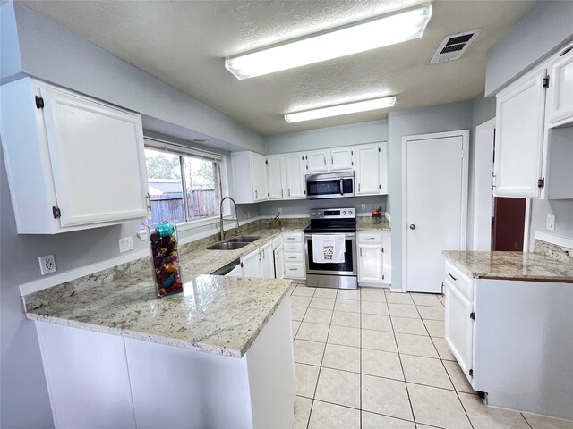 kitchen featuring appliances with stainless steel finishes, sink, kitchen peninsula, white cabinets, and light stone counters