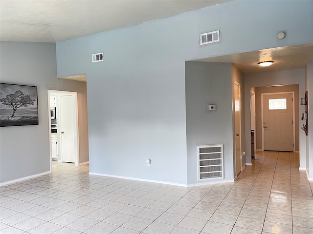 tiled empty room with a textured ceiling and a towering ceiling