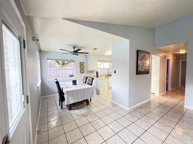 tiled dining room with sink, ceiling fan, a textured ceiling, and lofted ceiling