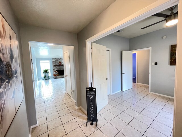 corridor featuring a textured ceiling and light tile patterned floors