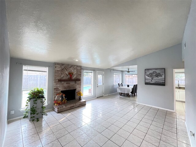 unfurnished living room with lofted ceiling, a stone fireplace, a textured ceiling, and light tile patterned floors