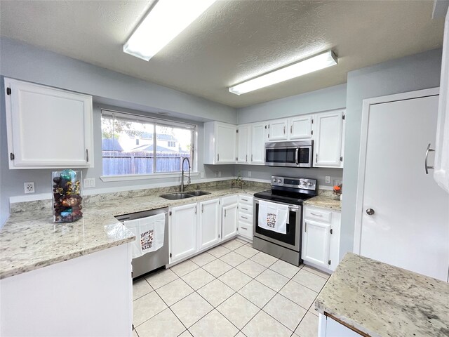 kitchen with sink, appliances with stainless steel finishes, light stone counters, and white cabinetry