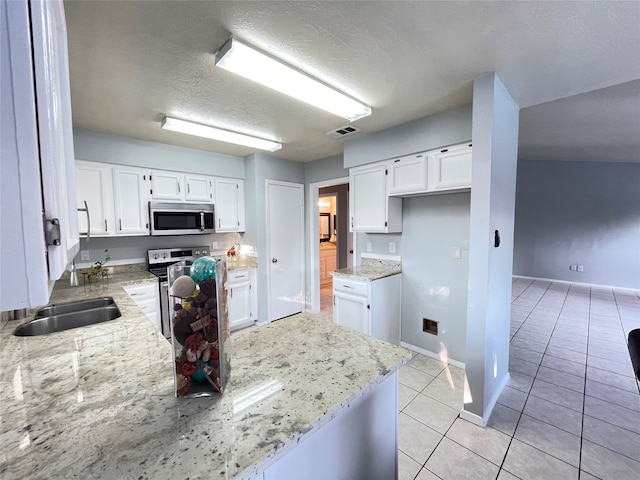 kitchen with white cabinets, light tile patterned floors, appliances with stainless steel finishes, a textured ceiling, and light stone counters