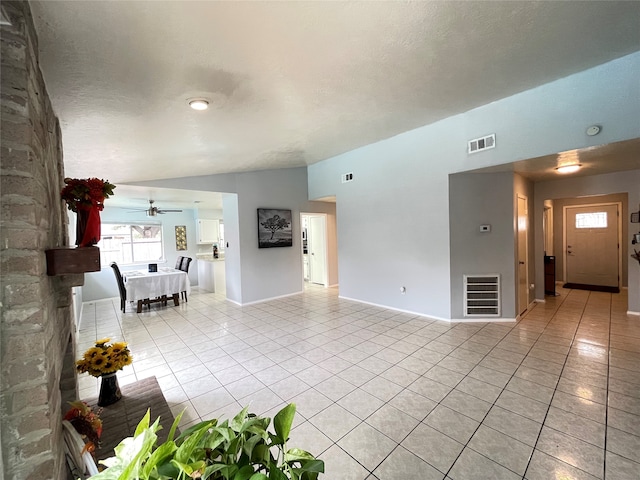 unfurnished living room featuring lofted ceiling, a textured ceiling, light tile patterned floors, and ceiling fan