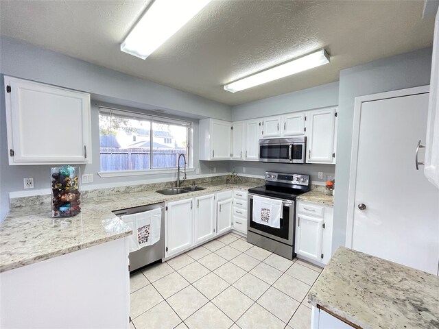 kitchen featuring light stone countertops, sink, appliances with stainless steel finishes, and white cabinetry