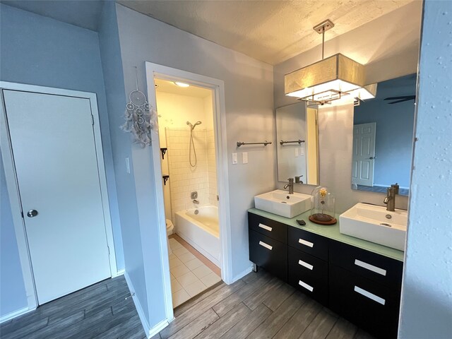 full bathroom featuring vanity, tiled shower / bath combo, hardwood / wood-style flooring, and toilet