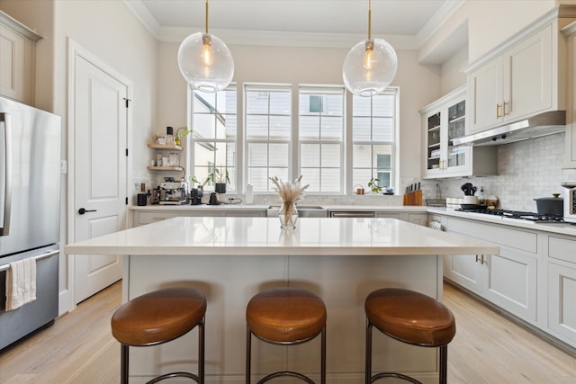 kitchen featuring light wood-type flooring, appliances with stainless steel finishes, a kitchen bar, and white cabinets