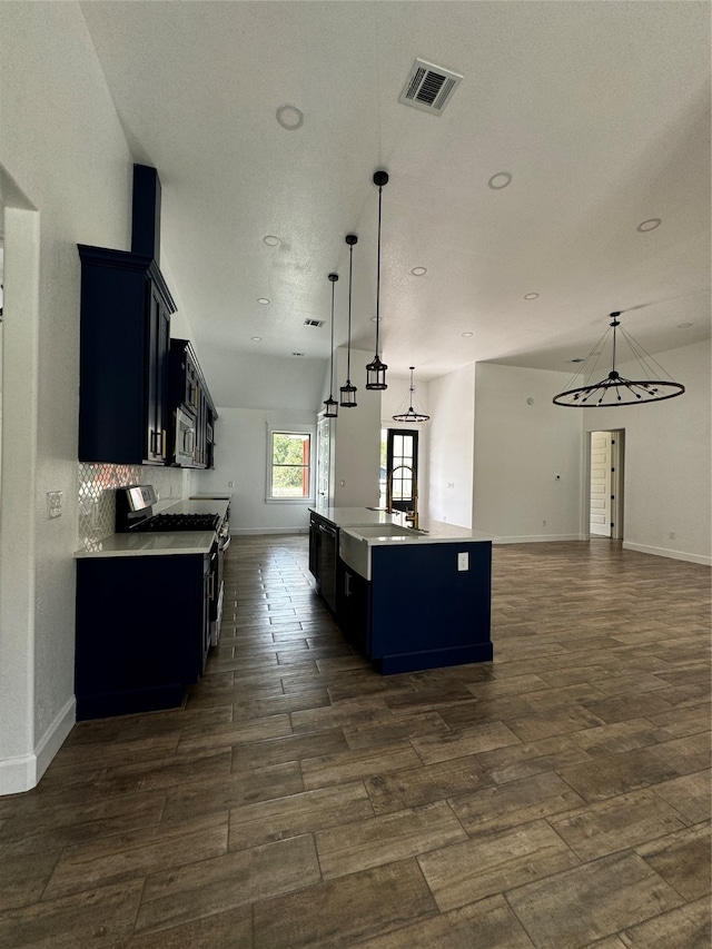 kitchen featuring dark hardwood / wood-style flooring, an island with sink, stainless steel appliances, and decorative light fixtures