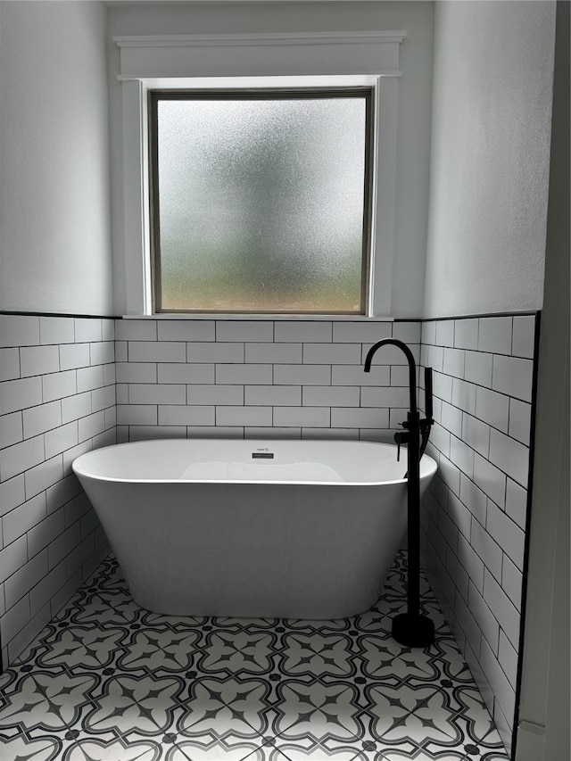 bathroom featuring a bathing tub, tile patterned flooring, and tile walls