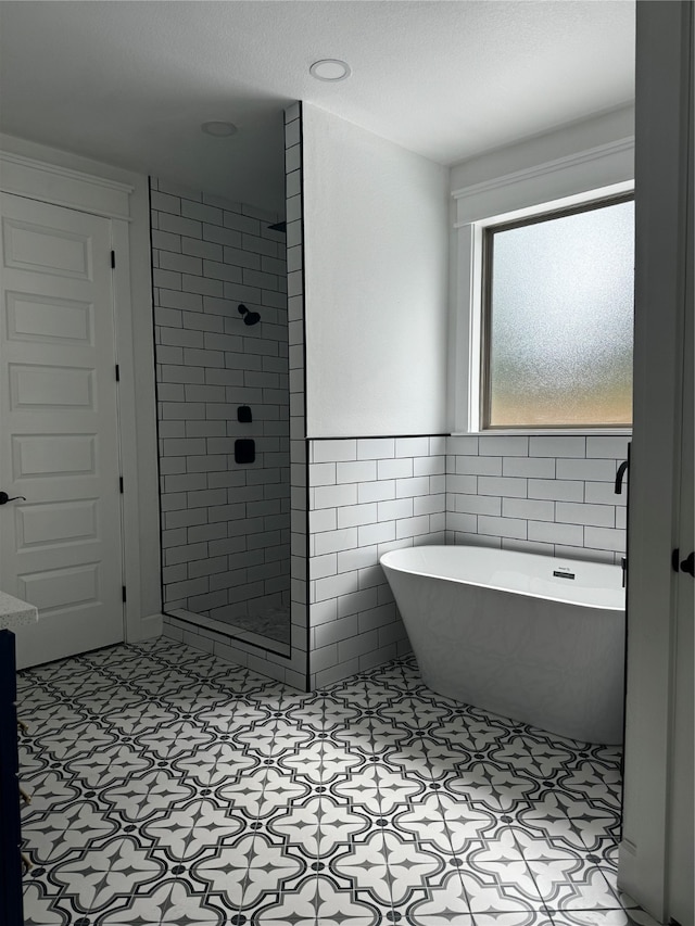 bathroom featuring tile patterned floors, tile walls, and independent shower and bath