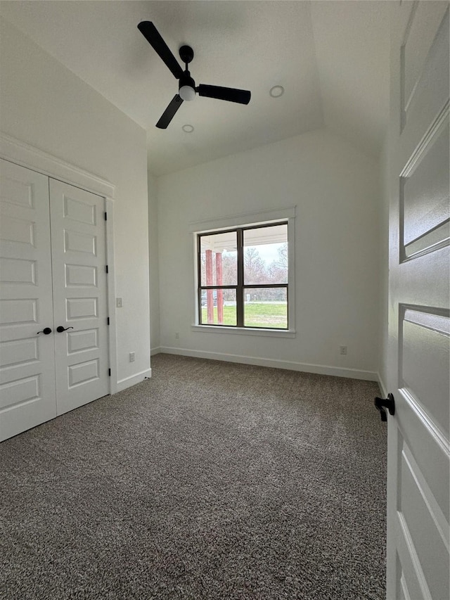 unfurnished bedroom with carpet, baseboards, vaulted ceiling, and a ceiling fan