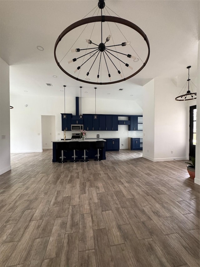 kitchen featuring a breakfast bar, a spacious island, open floor plan, hanging light fixtures, and stainless steel microwave