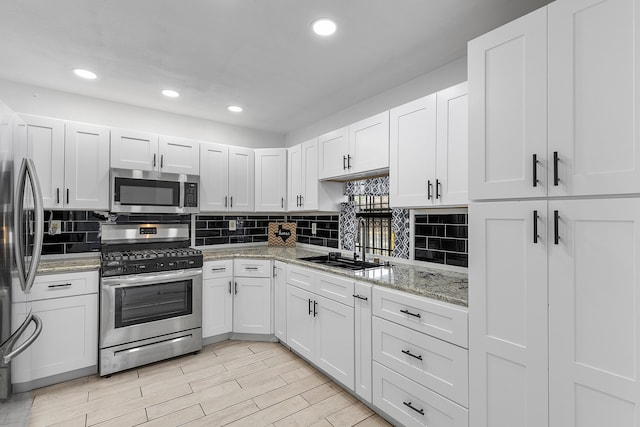 kitchen with tasteful backsplash, light stone counters, white cabinetry, sink, and stainless steel appliances