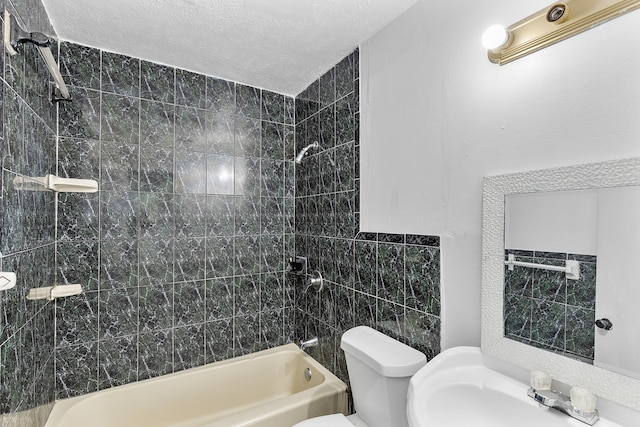 full bathroom with toilet, sink, tiled shower / bath combo, tile walls, and a textured ceiling