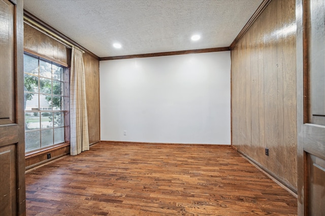 empty room featuring a textured ceiling, wooden walls, and dark wood-type flooring