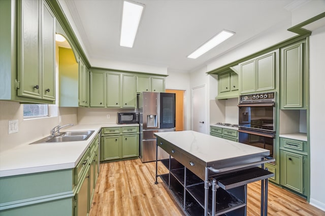 kitchen featuring light hardwood / wood-style floors, black appliances, green cabinetry, and sink