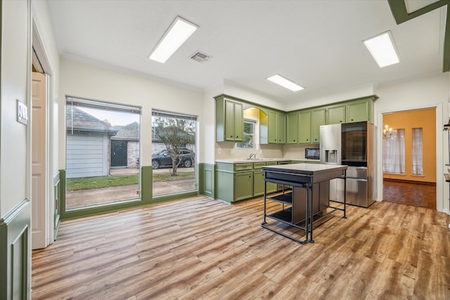 kitchen with a breakfast bar area, light hardwood / wood-style flooring, stainless steel refrigerator with ice dispenser, a center island, and green cabinetry